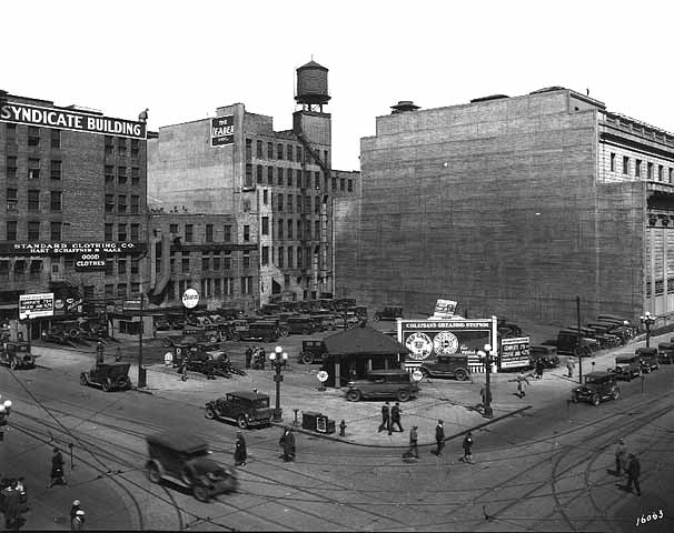 1925 - View of the corner of Sixth Street South and Marquette Avenue, including Coleman's Greasing Station, the rear of the Federal Reserve Bank, and the Syndicate Building in Minneapolis, MN (Minnesota Historical Society)