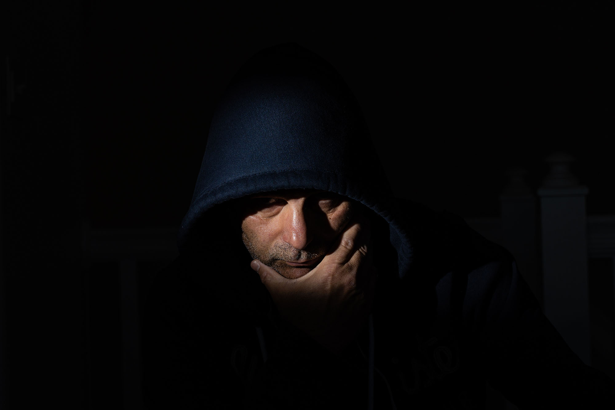 Malleck, dressed in a black hood and cloaked in shadow - original photo by Ivelin