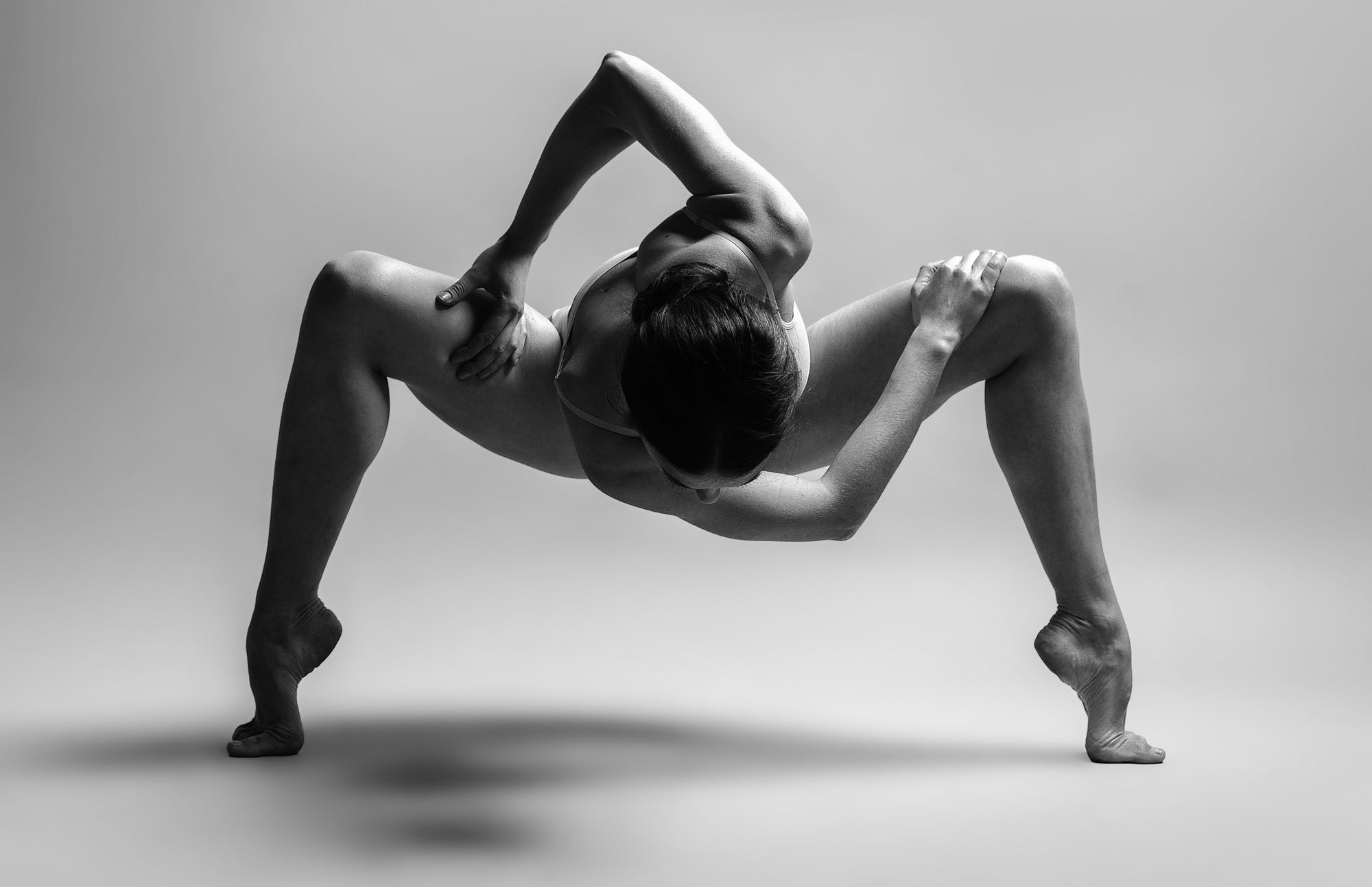 Athletic woman in an acrobatic full-body twist - photo by Vladee